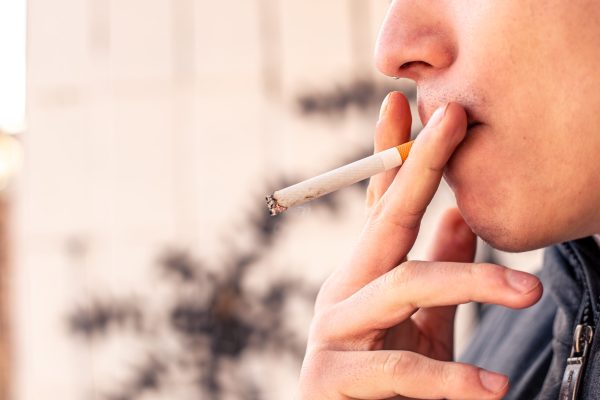 Smoking concept. Man smoking a cigarette. Harmful to health. High quality photo. Man holding a cigarette in his hands. Copy space.